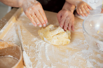 Close-up shot elderly woman hands kneading dough on wooden surface. Preparing dough for homemade pizza bread cookies muffin pie pasta . Kitchen equipment around large bowl sieve wooden spoon.