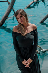 Girl in a black dress in blue water with dead trees