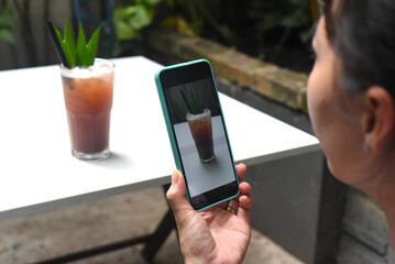 A woman taking picture of plum tea for advertisement 