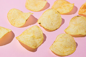Potato chips on a pink background. A delicious way to cook potatoes. Delicious fast food