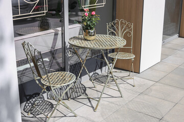 Forged chairs and a round table. Flowers on the table. Table for two. romantic concept