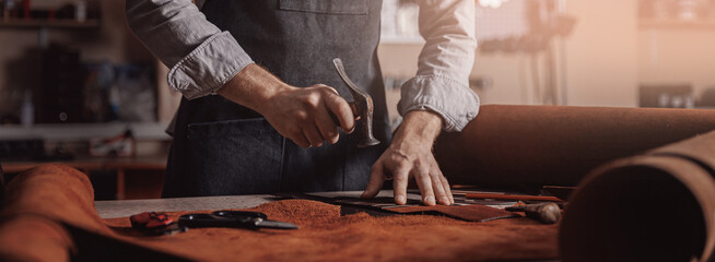 Tailor processing hammers seam on leather goods, Handmade craftsman - Powered by Adobe