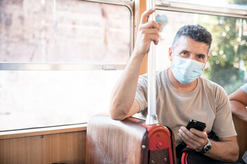 Senior old man on face medical mask while traveling inside public transport, tram Turkey