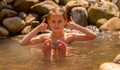 Young beautiful child girl  taking a bath at mountain geysers hot springs, thermal waters. Selective focus on feet.