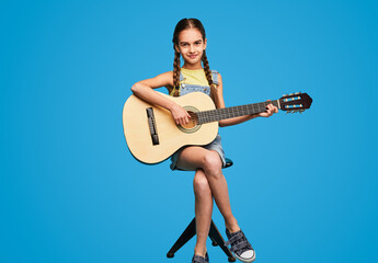 Teen student playing guitar on stool