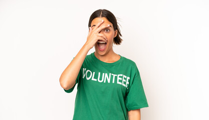 pretty hispanic woman looking shocked, scared or terrified, covering face with hand. ecology and...