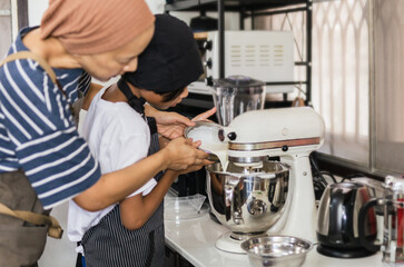 Mother teaching her son baking cake by pouring milk into a mixing bowl.
