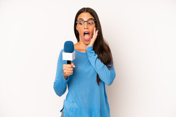 pretty hispanic woman feeling happy, excited and surprised. presenter with a microphone concept