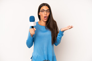 pretty hispanic woman feeling extremely shocked and surprised. presenter with a microphone concept