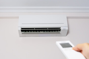 Man's hand with remote control turning on the air conditioner.