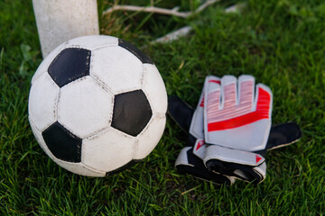 Soccer ball and goalkeeper gloves on football field.