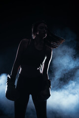 Silhouette portrait with white smoke in the background of a female model with boxing gloves