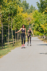Fototapeta na wymiar Full-length picture of sexy sportswomen rollerskating in the park