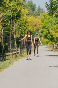 Full-length picture of sexy sportswomen rollerskating in the park