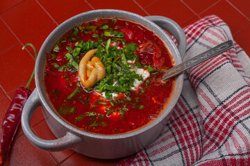 Bowl of red borsch with sour cream on cork stand on a red background. Borsch - beetroot soup, traditional dish of russian cuisine.