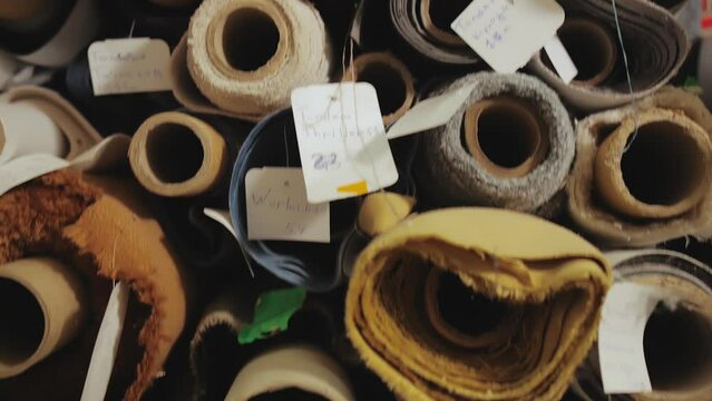 Rolls of fabric and textiles for sale stacked on shelves in shop. Close -up Warehouse various fabric, slow motion.