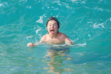 joyful boy bathes in sea waves on Cleopatra beach, Alanya, Antalya, Turkey