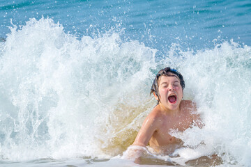 joyful boy bathes in sea waves on Cleopatra beach, Alanya, Antalya, Turkey