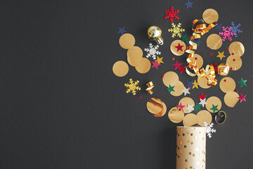 Modern colorful confetti popping from golden wrapping paper on black background, new year firework...