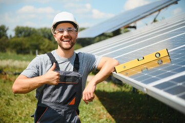 Male engineer in protective helmet installing solar photovoltaic panel system. Alternative energy ecological concept.