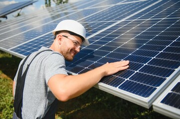 Fototapeta Male worker with solar batteries. Man in a protective helmet. Installing stand-alone solar panel system obraz