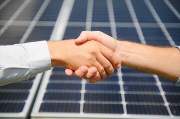 Two people having a shaking hands against solar panel after the conclusion of the agreement in the...