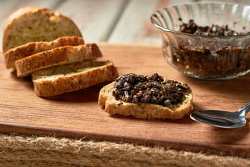 Black Olive Tapenade in bowl with spoon and Bread.