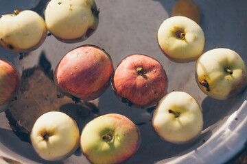Red and green apples in water in old bowl
