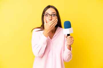 hispanic young adult woman covering mouth with hands with a shocked. interviewer with a microphone
