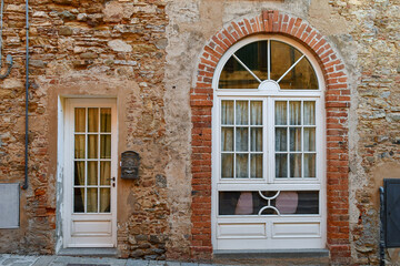 Fototapeta na wymiar White wooden window doors on the facade of an old brick house, Tuscany, Italy