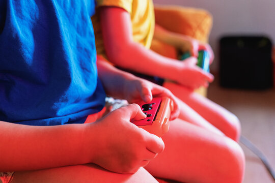 Anonymous children playing video game in evening time