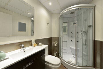 Bathroom with quarter circle shower cubicle with soothing jets, frameless mirror and white resin sink