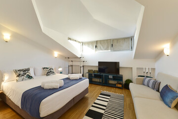 Bedroom with a double bed in the attic, blue details, white cushions and black and white cushions,...