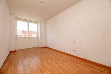 Empty room with white walls, wooden floors and aluminum window with views