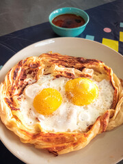 "roti sarang burung" on the table. It is pratha looks like bird nest with half cook eggs in the middle.