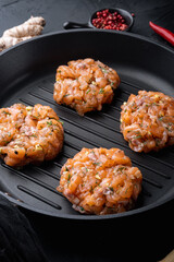 Raw quick asian salmon cutlets, on black textured background