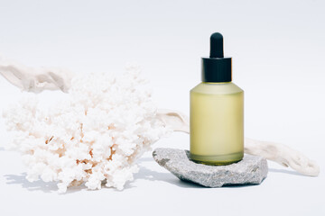 Fototapeta na wymiar Cosmetic oil with natural Dead Sea minerals in green glass dropper bottle against white background with sea corals. Algae oil or sea minerals based cosmetics products for skin care. Mockup image