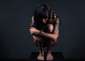 Photo of the woman squatting with yellow anaconda