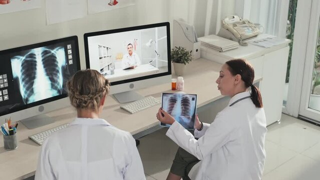 High angle shot of female doctors discussing chest x ray scan during online meeting via video call on computer
