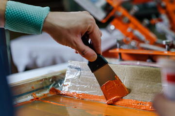 male hand with a spatula. serigraphy production selective focus photo. printing images on clothes by silk screen method in a design studio