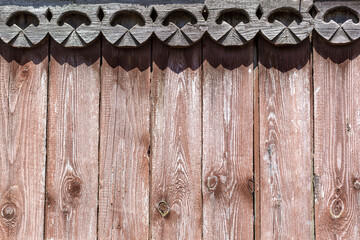 A wooden fence with a carved ornament in the form of curls on a sunny day. layout. Use it as a background. Copy space