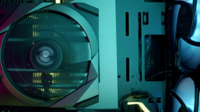 Close-up moving macro shot of the powerful gaming computer. Moving away from modern purple-turquoise video graphic card with three internal spinning coolers to the blue cooling system of the heatsink