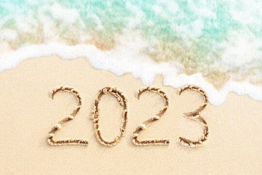2023 written in the sand with sea wave and beach background. New year concept photo. 
