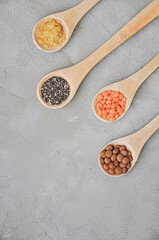 Different or various types of dry beans or dried legumes in wooden spoon on gray background. Whole grains, healthy food and diet concept. Top view. Flat lay