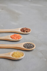 Different or various types of dry beans or dried legumes in wooden spoon on gray background. Whole grains, healthy food and diet concept