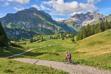Fototapeta na wymiar active senior woman, riding her electric mountain bike in the Arlberg mountain range near the famous village of Lech, Tirol, Austrian Alps