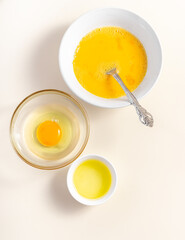 Raw eggs in a glass and white bowl on the table. Top View. Broken White Background. Place for Text.