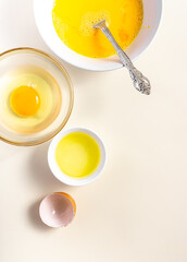 Raw eggs in a glass and white bowl on the table. Top View. Broken White Background. Place for Text.