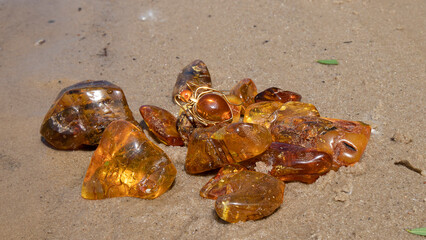 Shiny Baltic orange amber stones on the sand.  Material for jewelers. Alternative medicine.