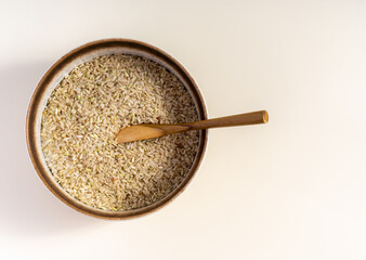 brown rice in a ceramic bowl and spoon isolated on white background with clipping path, top view